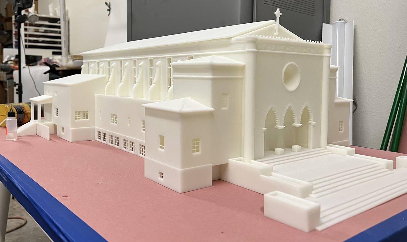 Large white 3D printed church architectural model with arched entry, stepped plaza and detailed windows on a shop table