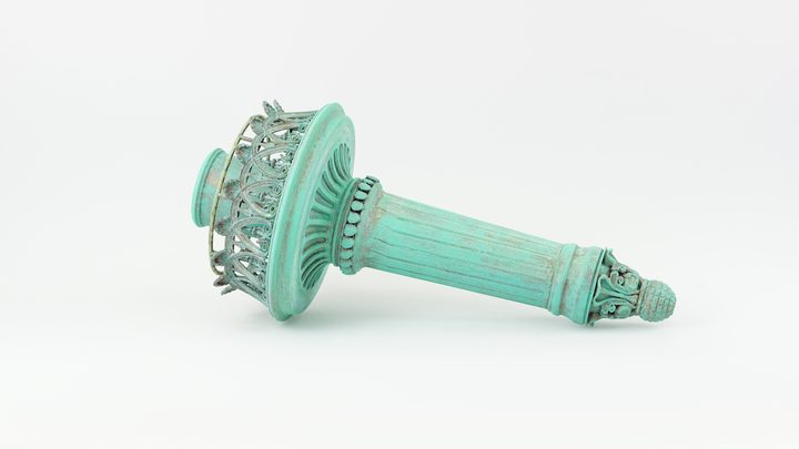 Ornate torch replica with a green verdigris patina and worn edges, photographed on a white background