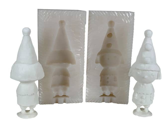 Two halves of a cream silicone mold with a gnome cavity, standing between two white cast gnome figures.